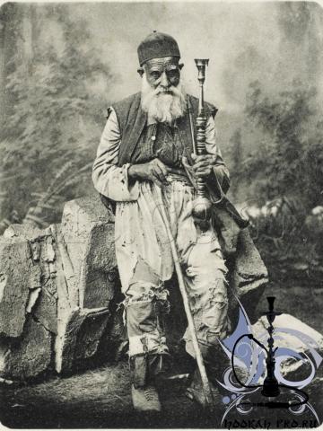Syrian venerable beggar seated holding his hookah pipe